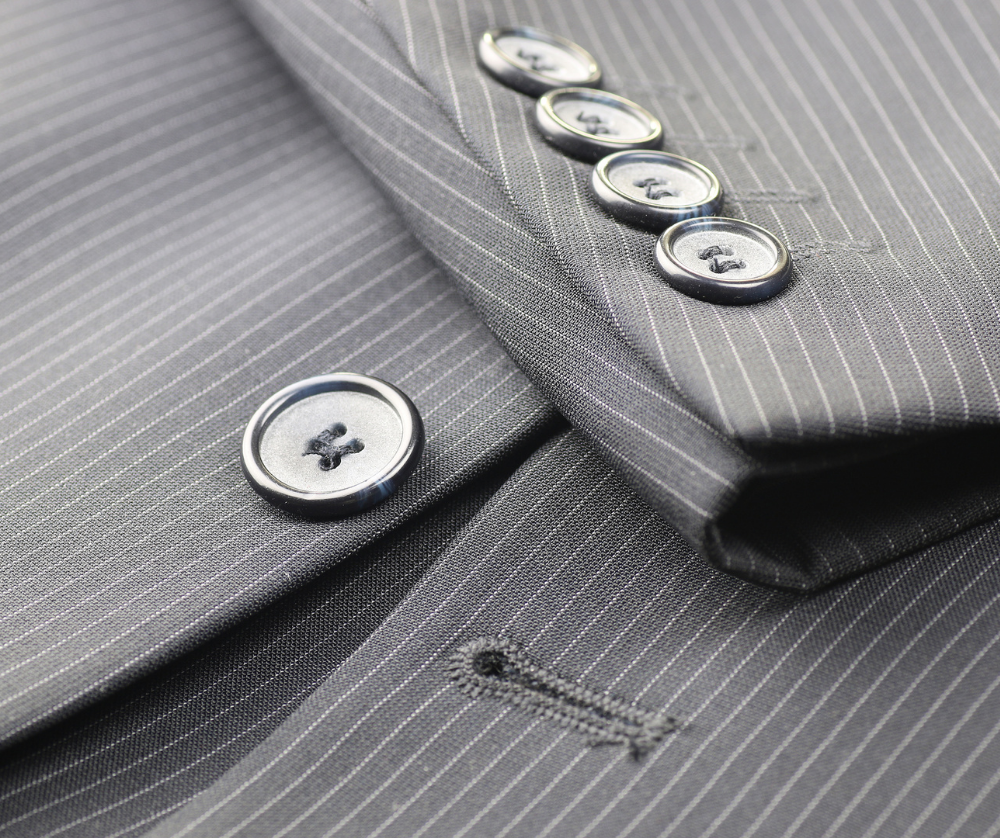 Close-up of custom suit craftsmanship featuring pinstripe fabric, horn buttons and hand finished tailoring details.